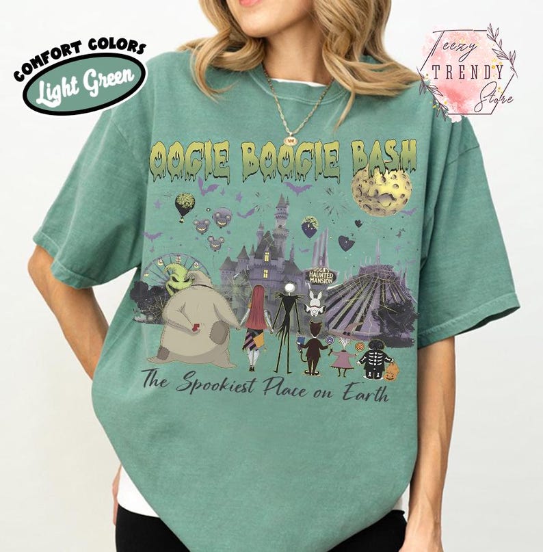 May include: A light green short-sleeve t-shirt featuring a graphic print with the text Oogie Boogie Bash and The Spookiest Place on Earth. The design includes various animated characters, a castle, a moon, and a Ferris wheel in dark tones.