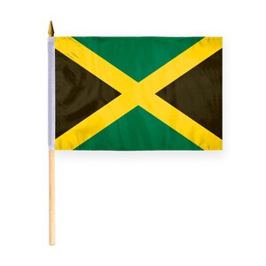 Puede incluir: Una peque&ntilde;a bandera jamaicana en un palo de madera. La bandera presenta una cruz diagonal amarilla que divide la bandera en cuatro secciones: dos tri&aacute;ngulos verdes y dos tri&aacute;ngulos negros. La bandera es rectangular y tiene un borde blanco.