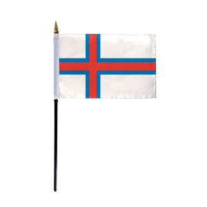 May include: A small desk flag of the Faroe Islands. The flag is white with a red cross outlined in blue.