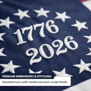 May include: Close-up of navy blue fabric with white embroidered stars and the numbers "1776" and "2026". The text "PREMIUM EMBROIDERY & STITCHING" and "Detailed stars with reinforced sewn stripe finish" are also visible.