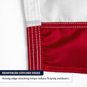 May include: Detail of a red and white flag corner. The flag has reinforced stitched edges with strong stitching to reduce fraying. The white section is at the top, and the red section is below.