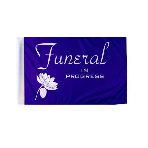 May include: A rectangular purple flag with the words "Funeral IN PROGRESS" in white script. A white lotus flower is on the left side. The flag has a white sleeve on the left side for hanging.