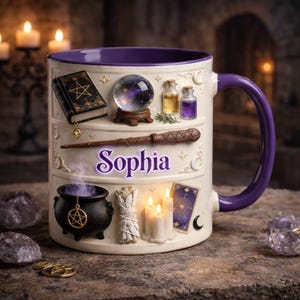 Puede incluir: Taza de cerámica blanca con asa y borde morados, con símbolos de brujería en relieve. La taza tiene una bola de cristal, una varita, un caldero y el nombre "Sophia" en morado. También tiene un libro pequeño, botellas, velas y una carta del tarot.