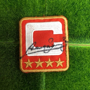 May include: Red and gold embroidered patch with a white letter "C" and three gold stars. The letter "C" is outlined in white and has a small image of a record player inside.