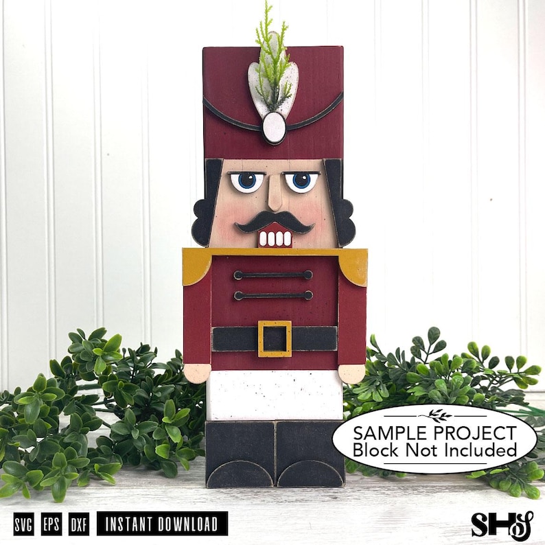 May include: A wooden nutcracker figure featuring a tall maroon hat with a white feather accent, a maroon jacket with gold shoulder details, a black belt with a gold buckle, white trousers, and black boots, with a moustache and blue eyes.