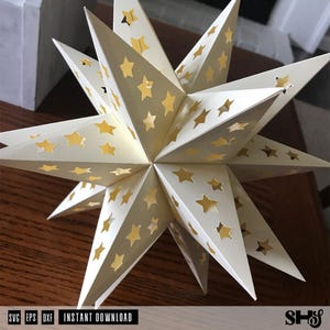 May include: A three-dimensional off-white paper star ornament featuring multiple pointed tips and numerous star-shaped cutouts that reveal a gold-colored interior. The object displays a geometric structure with sharp edges and symmetrical star patterns.