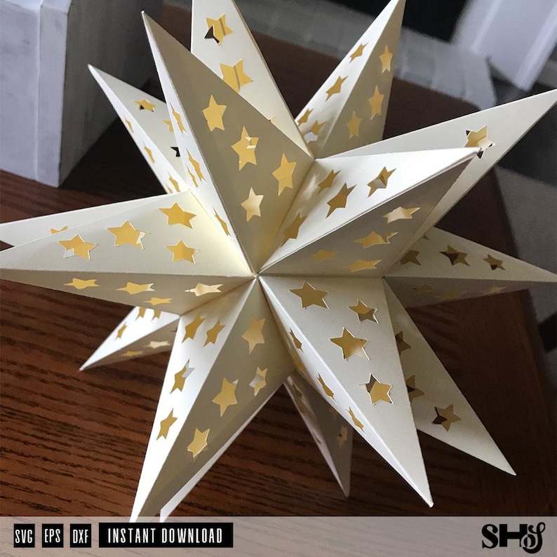 May include: A three-dimensional off-white paper star ornament featuring multiple pointed tips and numerous star-shaped cutouts that reveal a gold-colored interior. The object displays a geometric structure with sharp edges and symmetrical star patterns.