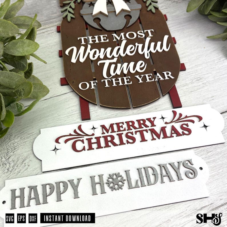 May include: A brown wooden sled decoration featuring a grey bell, a white bow, and the text THE MOST WONDERFUL TIME OF THE YEAR. Below are two white rectangular signs, one with red MERRY CHRISTMAS text and one with grey HAPPY HOLIDAYS text.