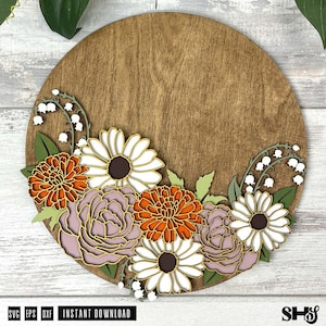 May include: A round wooden sign with a floral design. The design features white, orange, and purple flowers with green leaves. The flowers are arranged in a cluster at the bottom of the sign.