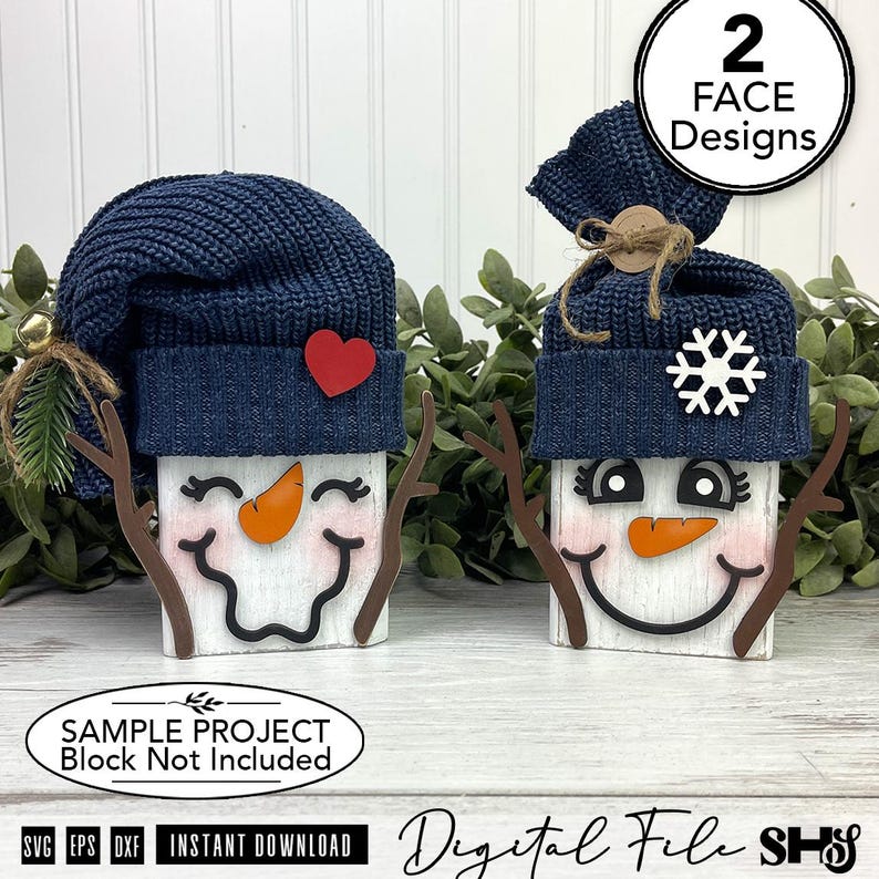 May include: Two wooden block snowman decorations featuring navy blue knit hats. One snowman has a red heart, the other a white snowflake. Both have orange carrot noses, brown twig arms, and painted faces. Text includes 2 FACE DESIGNS and SAMPLE PROJECT.