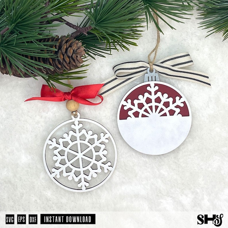 May include: Two circular Christmas ornaments featuring snowflake designs. One ornament is a white cutout snowflake with a red ribbon and wooden bead. The other is a solid white and maroon circle with a cutout snowflake top and a striped ribbon.