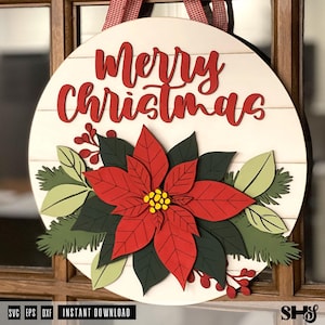 K&ouml;nnte beinhalten: Ein rundes T&uuml;rschild aus Holz mit dem roten Schriftzug Merry Christmas oben. In der Mitte befindet sich ein mehrschichtiger Weihnachtsstern mit roten Bl&uuml;tenbl&auml;ttern und gelber Mitte, umgeben von dunkelgr&uuml;nen Bl&auml;ttern und roten Beeren.
