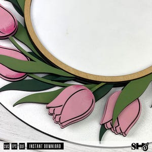 May include: A circular wooden frame with a white center panel, decorated with layered pink tulip flowers and dark green leaves. The design features black outlines on the petals and foliage. Text at the bottom reads SVG, EPS, DXF, INSTANT DOWNLOAD, SHS.