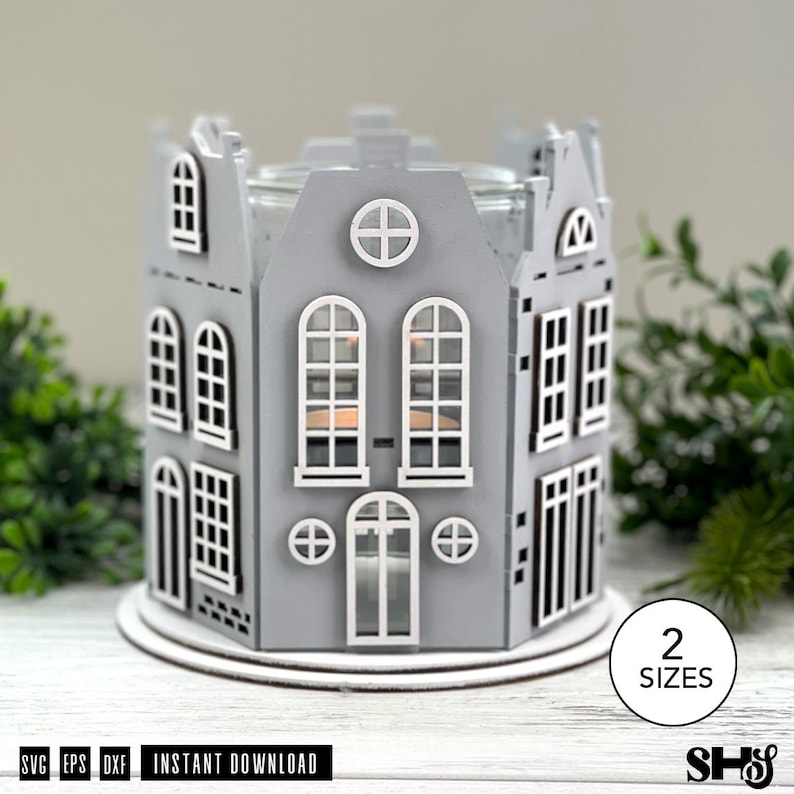 May include: A gray laser-cut wooden candle holder shaped like a miniature house with multiple windows and doors. The structure features a circular window at the top and a central arched doorway. A circular base supports the house-shaped frame.