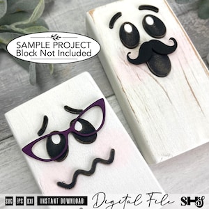 May include: Two rectangular white wooden blocks featuring decorative facial features. One block displays black eyebrows, eyes, and a mustache. The other block features black eyebrows, eyes, a wavy mouth, and purple cat-eye glasses frames.
