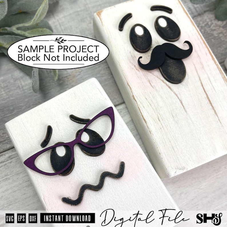 May include: Two rectangular white wooden blocks featuring decorative facial features. One block displays black eyebrows, eyes, and a mustache. The other block features black eyebrows, eyes, a wavy mouth, and purple cat-eye glasses frames.