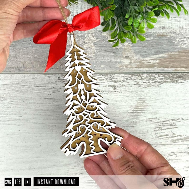 Puede incluir: Un adorno de &aacute;rbol de Navidad de madera con un contorno blanco y un intrincado dise&ntilde;o recortado. Est&aacute; adornado con un lazo de sat&eacute;n rojo y una percha de hilo. El adorno est&aacute; sostenido por las manos de una persona. La parte inferior de la imagen tiene el texto "SVG EPS DXF INSTANT DOWNLOAD".