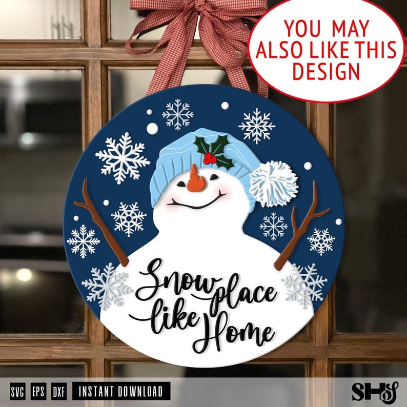 K&ouml;nnte beinhalten: Ein rundes dunkelblaues Schild mit einem wei&szlig;en Schneemann, der eine hellblaue Strickm&uuml;tze, eine orangefarbene Karottennase und braune Ast-Arme tr&auml;gt. Das Design zeigt wei&szlig;e Schneeflocken und den schwarzen Schriftzug Snow place like Home.