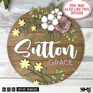 K&ouml;nnte beinhalten: Ein rundes Holzschild mit einem floralen Design und dem Namen "Sutton Grace" in wei&szlig;er und rosa Schrift.