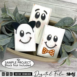 May include: Three rectangular white wooden blocks featuring black ghost faces. One block has black cat ears, one has a surprised expression, and one features an orange polka dot bow tie. The image includes text stating SAMPLE PROJECT Block Not Included.