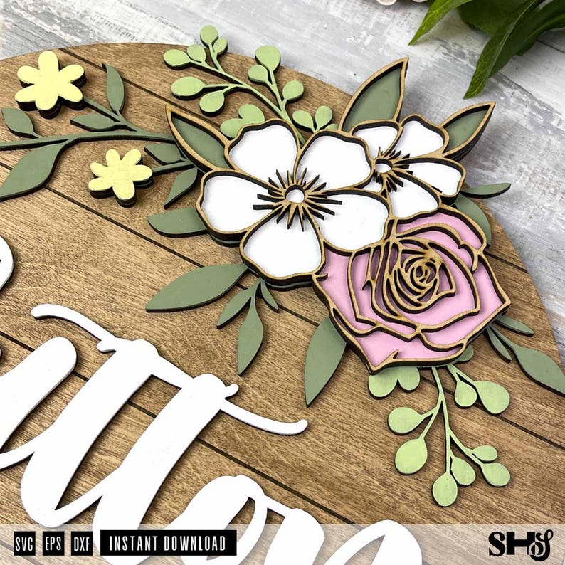 Puede incluir: Un letrero de pared circular de madera con recortes en capas de flores blancas y rosas, hojas verdes y peque&ntilde;as flores amarillas. El letrero incluye letras cursivas blancas y el texto SVG, EPS, DXF, INSTANT DOWNLOAD y SHS.