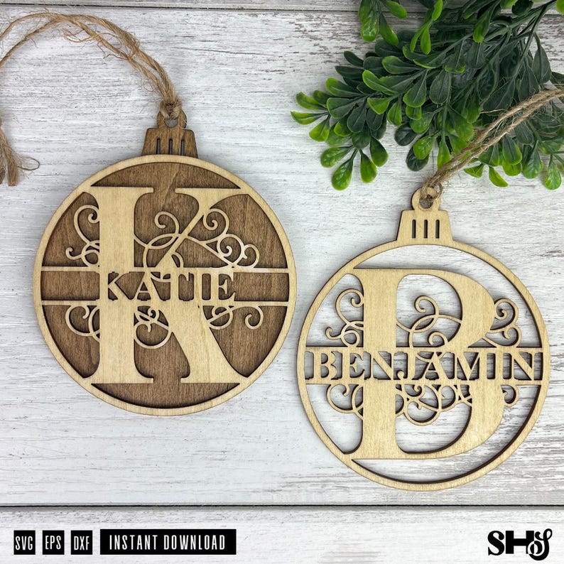 Op de afbeelding: Twee ronde houten ornamenten met lasergesneden ontwerpen. Het ene ornament toont een grote letter K met de naam KATIE erin verwerkt, en het andere een grote letter B met de naam BENJAMIN erin verwerkt. Beide hebben lussen van touw.