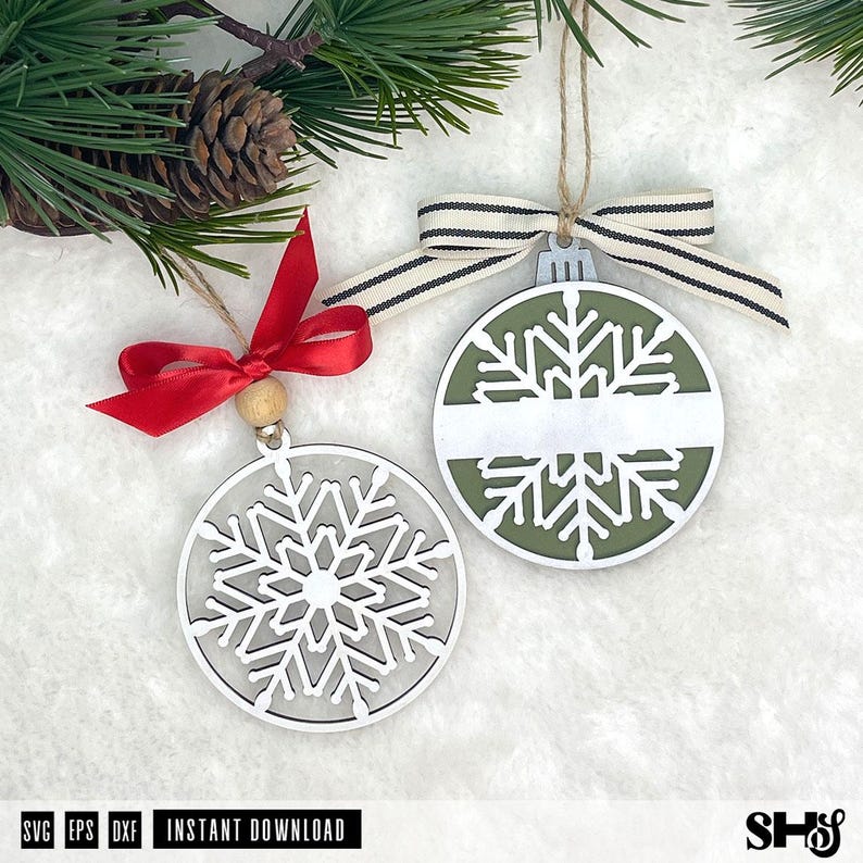 May include: Two circular snowflake ornaments. One is white with a red ribbon and wooden bead. The other is olive green with a white centre stripe and a black and white striped ribbon. Both feature intricate snowflake cutouts and twine loops.