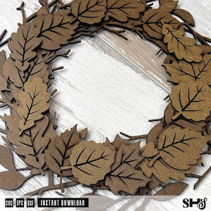 Puede incluir: Una corona circular compuesta por hojas de madera marr&oacute;n cortadas con l&aacute;ser y ramitas finas. El dise&ntilde;o presenta varias formas de hojas con detalles de venas grabados dispuestos en un patr&oacute;n superpuesto. El texto SVG, EPS, DXF, INSTANT DOWNLOAD, SHS es visible.