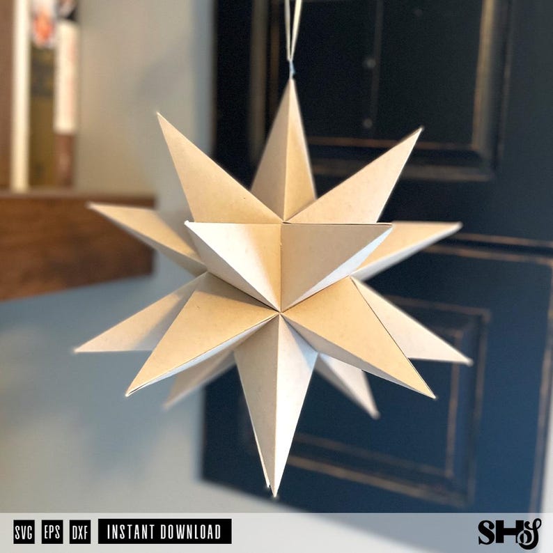 May include: A three-dimensional star ornament constructed from light beige paper with multiple sharp, pointed triangular facets. The geometric structure is suspended by a thin white string, featuring a complex, symmetrical design with many radiating points.
