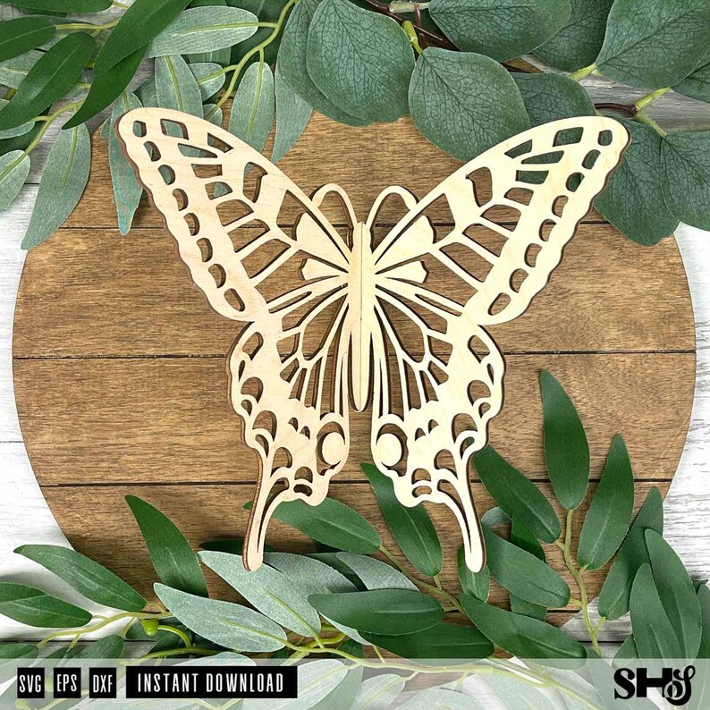 May include: A light-colored wooden butterfly cutout featuring intricate laser-cut wing patterns with symmetrical geometric shapes. The butterfly is positioned centrally, displaying a detailed openwork design across both wings and the body.