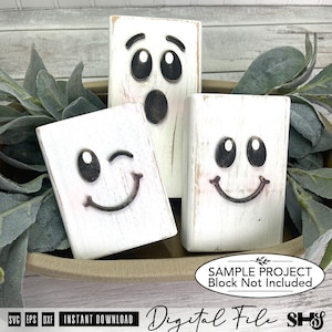 May include: Three rectangular white wooden blocks with distressed finishes, each featuring a dark metal ghost face. One block shows a surprised expression, while the other two display smiling faces, with one of those winking. Text reads: SAMPLE PROJECT Block Not Included.
