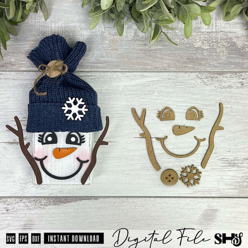 May include: A snowman craft kit featuring a white wooden block with a painted face, a dark blue knit hat with a white snowflake, and two brown twig arms. The kit includes additional wooden cutouts of eyes, a nose, a mouth, arms, and a snowflake.