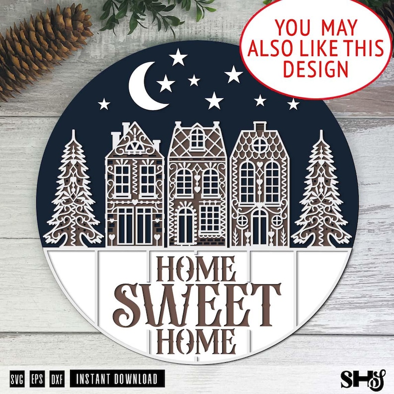 K&ouml;nnte beinhalten: Ein rundes Wandschild mit einem dunkelblauen Nachthimmel, einer wei&szlig;en Mondsichel und Sternen &uuml;ber drei braun-wei&szlig;en Lebkuchenh&auml;usern und zwei Tannenb&auml;umen. Der Schriftzug "HOME SWEET HOME" ist in Braun auf wei&szlig;em Hintergrund abgebildet.
