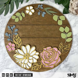 Op de afbeelding: Een rond houten bord met een bloemmotief. Het bord heeft een lichtbruine houten achtergrond met een witte madeliefje, een roze roos en groene bladeren. Het bord heeft de tekst "INSTANT DOWNLOAD" onderaan.