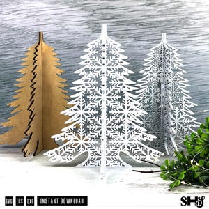 Può includere: Tre alberi di Natale decorativi. Uno è marrone, il secondo è bianco con ritagli di fiocchi di neve e il terzo è argento con ritagli di fiocchi di neve. Gli alberi sono in legno e sono in piedi. Il testo "SVG EPS DXF INSTANT DOWNLOAD" è in basso.