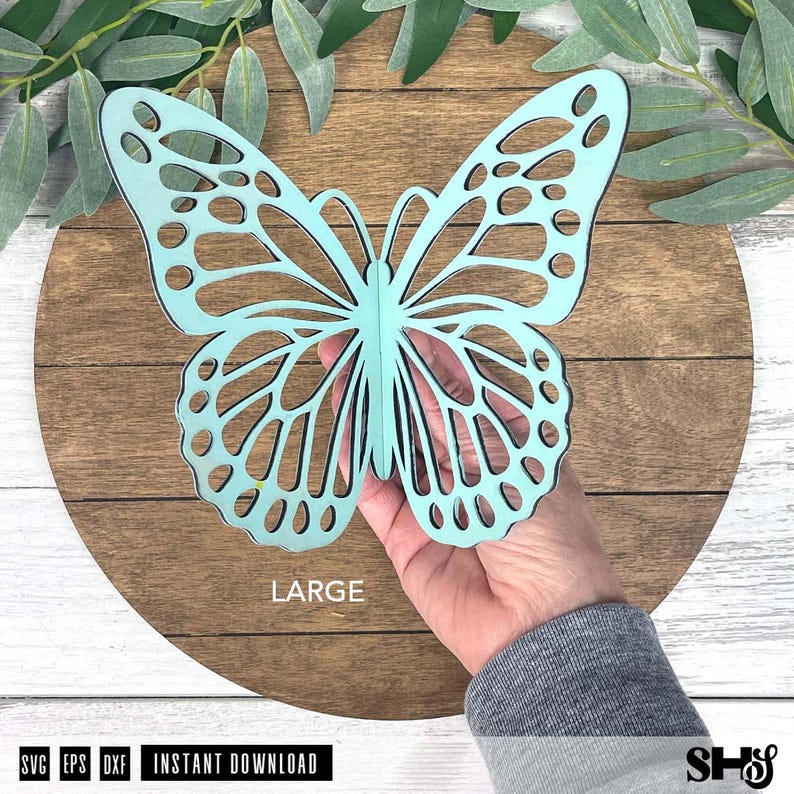 May include: A light blue butterfly cutout with intricate wing patterns and cutouts. The butterfly is held in a hand and features the word LARGE printed in white text below it. The bottom of the image includes the text SVG EPS DXF INSTANT DOWNLOAD.