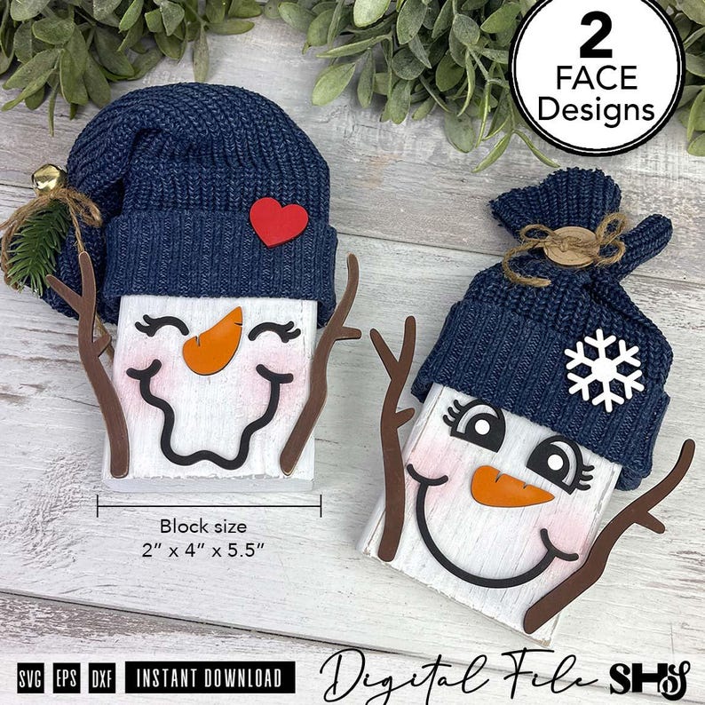 May include: Two snowman figures made of white blocks with navy blue knit hats, orange carrot noses, and brown branch-like arms. One features a red heart, the other a white snowflake. Text indicates 2 face designs and a 2 inch by 4 inch by 5.5 inch block size.