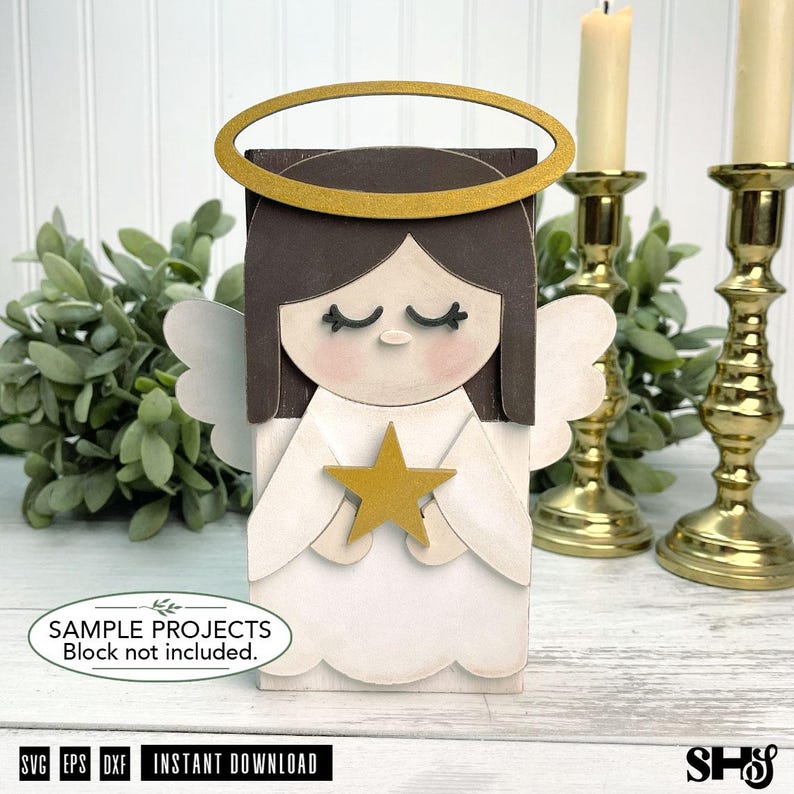 Op de afbeelding: Een houten engelfiguur met donkerbruin haar, een gouden halo en witte vleugels. De engel heeft gesloten ogen, roze wangen en houdt een gouden ster vast. Een wit ovaal label onderaan vermeldt: SAMPLE PROJECTS Block not included.