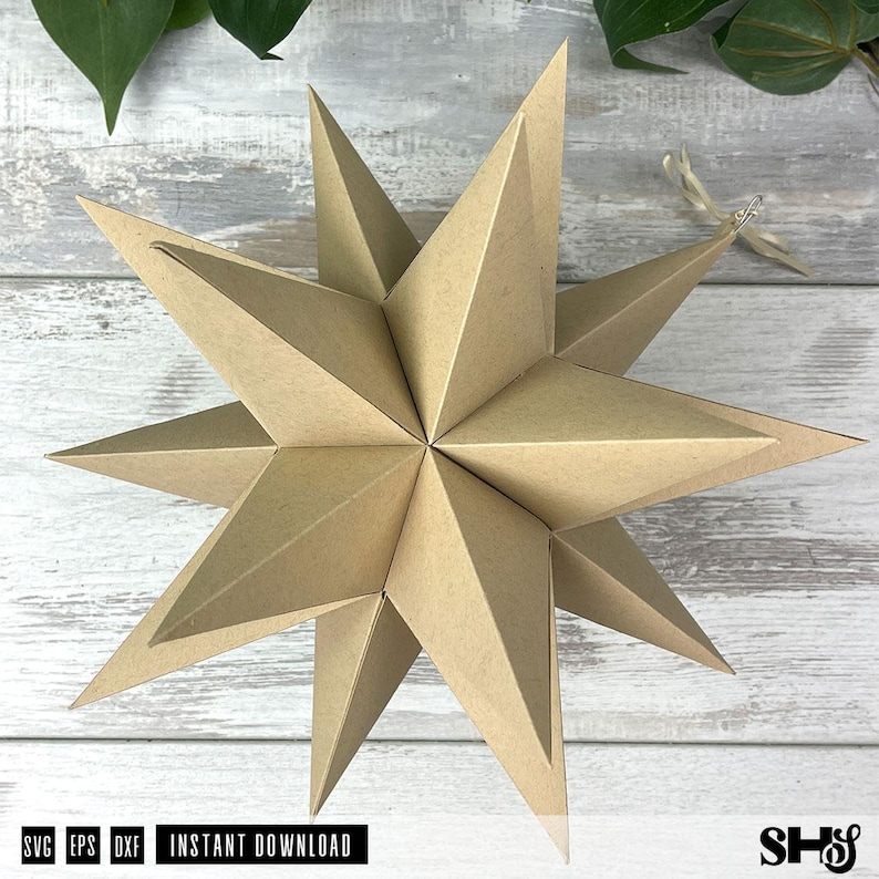 May include: A three-dimensional star ornament constructed from light brown paper with multiple pointed rays extending from a central point. A thin, light-colored ribbon is attached to one of the star's points for hanging purposes.