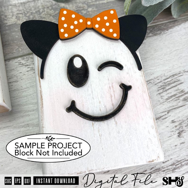 May include: A white wooden block featuring a ghost face with black eyes and a curved mouth. The ghost has black ears and an orange bow with white polka dots attached to the top. The text on the image reads: SAMPLE PROJECT Block Not Included.