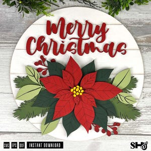 K&ouml;nnte beinhalten: Ein rundes wei&szlig;es Holzschild mit horizontalen Plankenlinien und dem roten Schriftzug Merry Christmas. Das Schild ist mit geschichteten Ausschnitten einer gro&szlig;en roten Weihnachtssternbl&uuml;te, dunkelgr&uuml;nen Bl&auml;ttern, hellgr&uuml;nen Bl&auml;ttern und roten Beeren verziert.