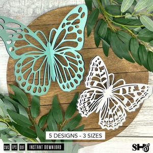 May include: Two intricate butterfly cutouts, one in light teal and one in white, featuring detailed wing patterns. The text 5 DESIGNS - 3 SIZES and INSTANT DOWNLOAD is visible, along with file format labels SVG, EPS, DXF, and the initials SHS.