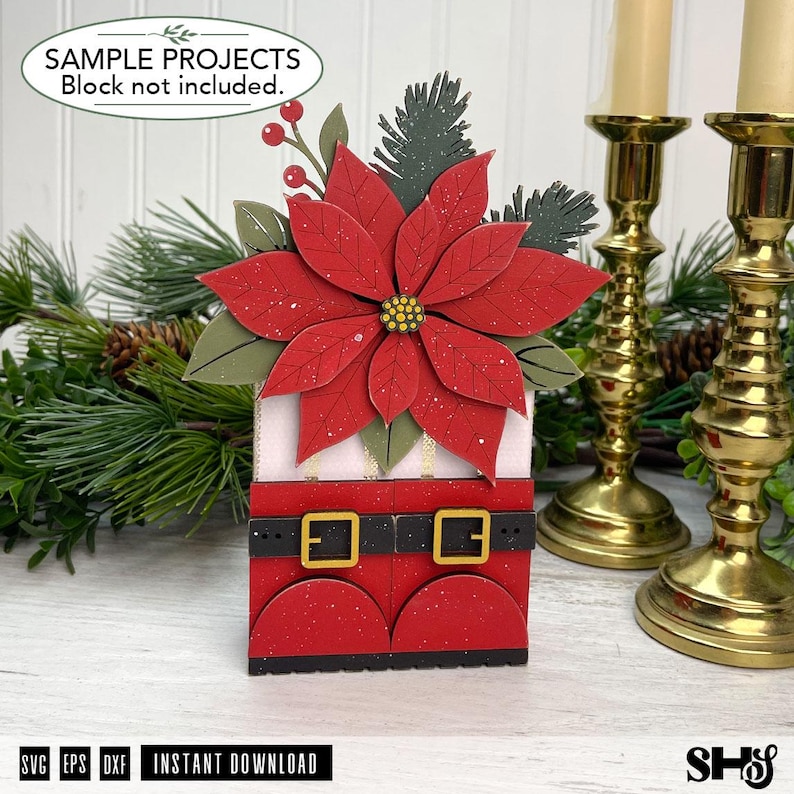May include: A decorative craft project featuring a large red poinsettia flower with green leaves and pine sprigs atop a red base resembling Santa Claus boots with black belts and gold buckles. The text reads SAMPLE PROJECTS Block not included.