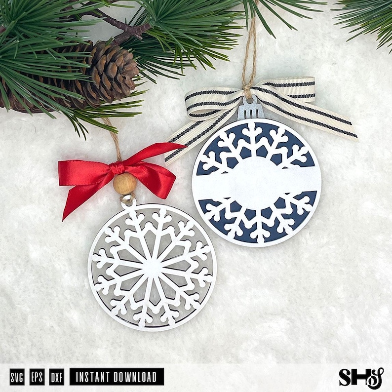 May include: Two circular snowflake ornaments. One is white with a grey background and a red satin ribbon bow. The other is white with a dark blue background, a horizontal white centre bar, and a beige and black striped ribbon bow.
