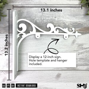 Może przedstawiać: Biały metalowy wspornik do szyldu z ozdobnymi zawijasami, o wymiarach 33,3 cm szerokości i 33,5 cm wysokości. Wspornik posiada dwa punkty zawieszenia oraz tekst: Display a 12-inch sign. Hole template and hanger included. SVG EPS DXF.