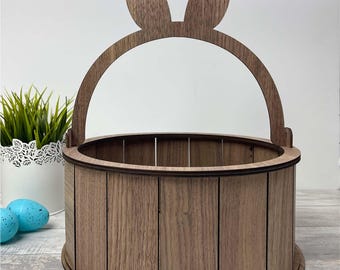 May include: A wooden Easter basket with bunny ears. The basket is brown and has a wood grain pattern. The basket has a handle and is perfect for holding Easter eggs.