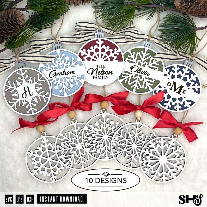 May include: A collection of ten circular Christmas ornaments featuring intricate snowflake cutouts. Five ornaments are solid with personalised text and names, while five are open-work white wood designs with red ribbon bows and wooden beads.