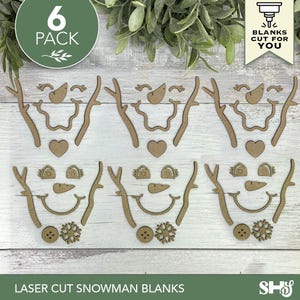 May include: A 6-pack of laser-cut wooden snowman face blanks. Each set includes two twig-like arms, a carrot-shaped nose, a curved mouth, two eyes, and decorative accents like hearts, buttons, or snowflakes in a light brown wood finish.