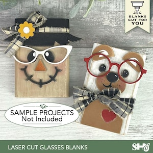 May include: Two wooden block figures, one a scarecrow with white cat-eye glasses and the other a dog with red glasses. Both have decorative bows. The text reads "SAMPLE PROJECTS Not Included" and "LASER CUT GLASSES BLANKS".