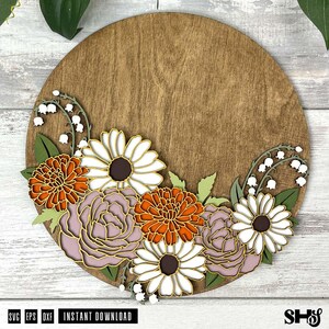 K&ouml;nnte beinhalten: Ein rundes Holzschild mit einem floralen Design. Die Blumen sind wei&szlig;, orange und rosa. Das Schild ist perfekt f&uuml;r eine Bauernhaus- oder rustikale Dekoration.